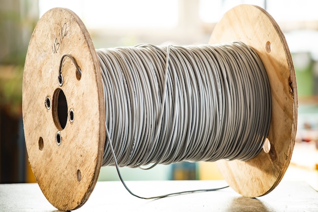 Primer plano de una madeja gigante de cables grises en un carrete de madera en la fabricación de equipos eléctricos. El concepto de tecnología moderna y volúmenes industriales.