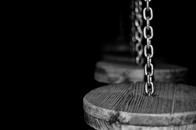 Foto primer plano de madera colgada de cadenas contra un fondo negro