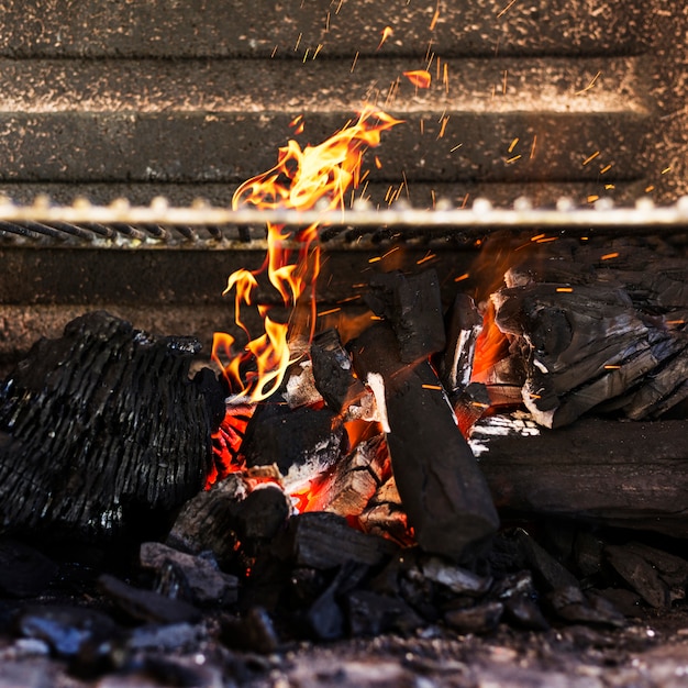 Foto primer plano de una madera en llamas en la parrilla de la barbacoa
