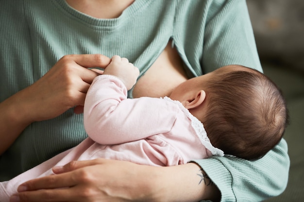 Primer plano de la madre alimenta a su hijo del mes con leche materna en casa