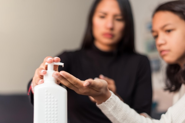 Primer plano de la madre aplicando gel de limpieza a su hija en casa