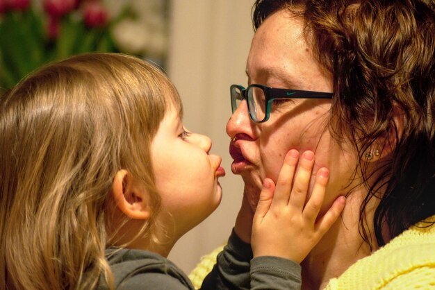 Un primer plano de una madre besando a su hija linda.