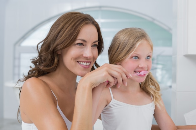 Primer plano de la madre con hija cepillarse los dientes