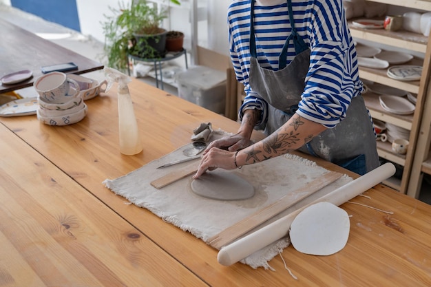 El primer plano de una maestra de cerámica femenina crea un plato artesanal del concepto de terapia de arte de olla húmeda