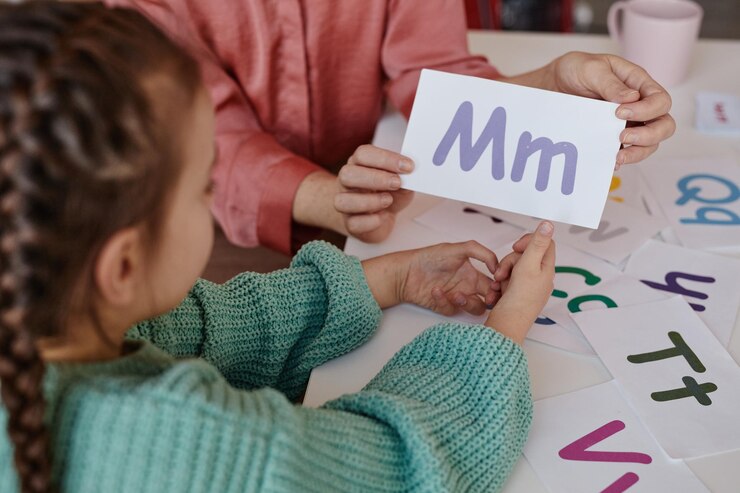 Foto primer plano del maestro mostrando la tarjeta con la carta a la niña mientras aprenden inglés en la mesa