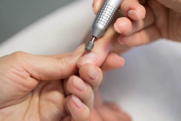 Primer plano de manicurista haciendo manicura de hardware a una joven