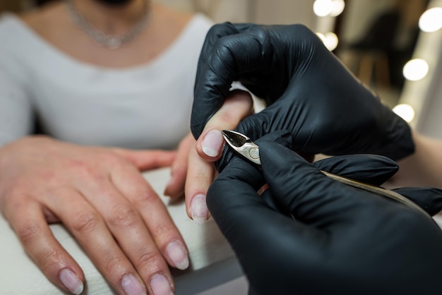 Primer plano de un manicurista quitando cutículas con cortaúñas