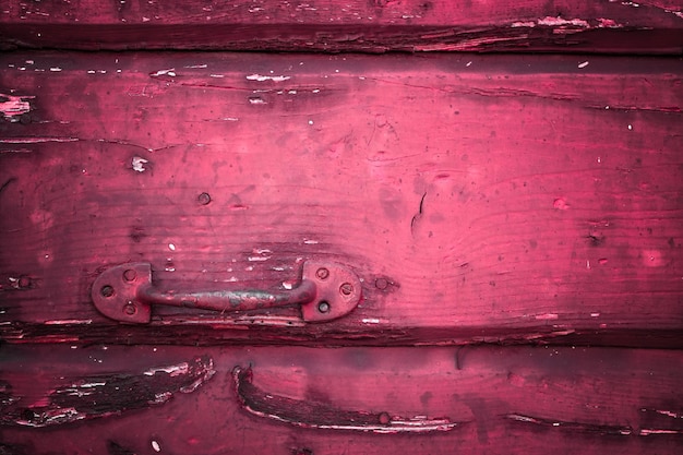 Un primer plano de una manija oxidada en una vieja puerta roja