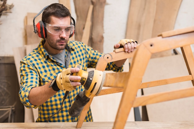 Primer plano de un manitas lijar muebles de madera en taller