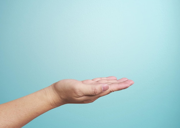 Primer plano de la mano aislado sobre fondo azul Palma hacia arriba