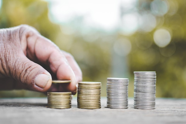 Primer plano de una mano apilando monedas en la mesa