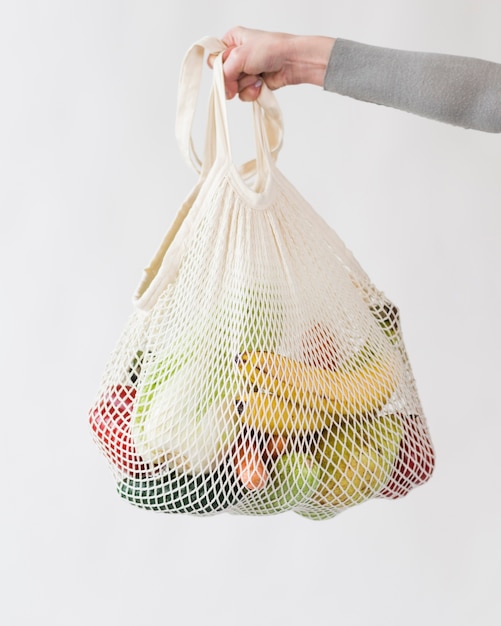 Primer plano mano bolsa reutilizable con frutas y verduras
