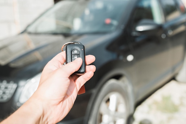 Primer plano de la mano caucásica humana usando el control remoto de la llave del coche Alarma de coche