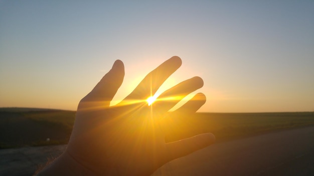 Foto primer plano de la mano contra el atardecer