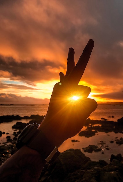 Foto primer plano de la mano contra el cielo durante la puesta de sol