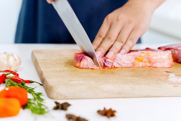 Primer plano de la mano cortando carne roja con un cuchillo