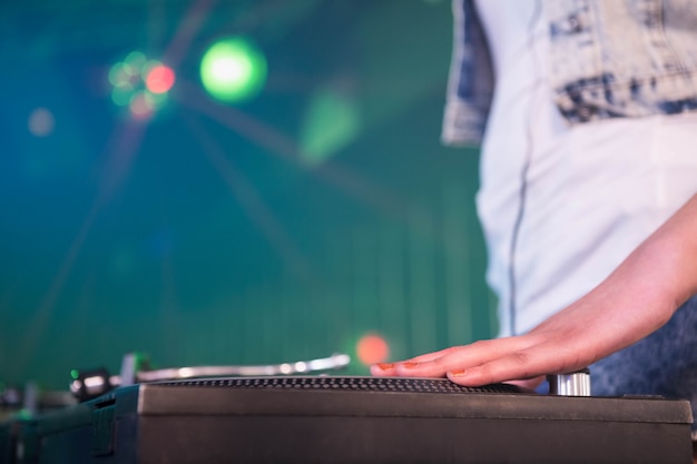 Primer plano de una mano de DJ femenina en un disco en la discoteca