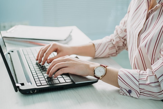 Primer plano de la mano de la empresaria haciendo notas en el calendario en la computadora portátil mano femenina escribiendo