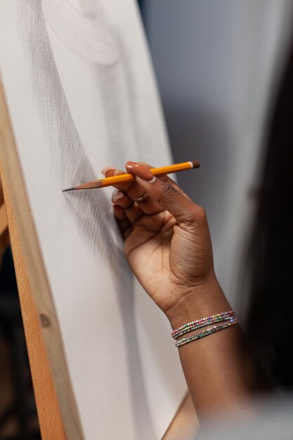 Primer plano de la mano de un estudiante de arte sosteniendo un jarrón de dibujo a lápiz gráfico sobre lienzo trabajando en un proyecto artístico para la escuela. Mujer pintor dibujando ilustración usando herramientas de pintura profesional