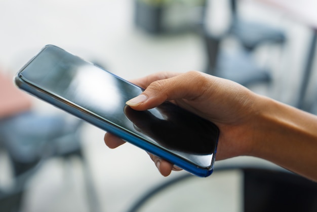 Primer plano de mano femenina control de noticias en el teléfono