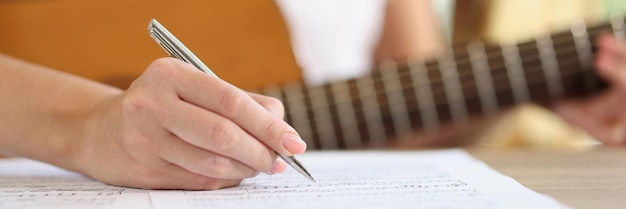 Primer plano de la mano femenina escribiendo notas de una nueva canción nuevas ideas cantante inspirador componiendo música