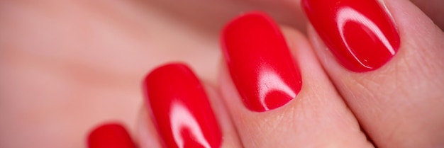 Primer plano de mano femenina con esmalte de gel rojo brillante uñas de mujer hermosa con perfecto