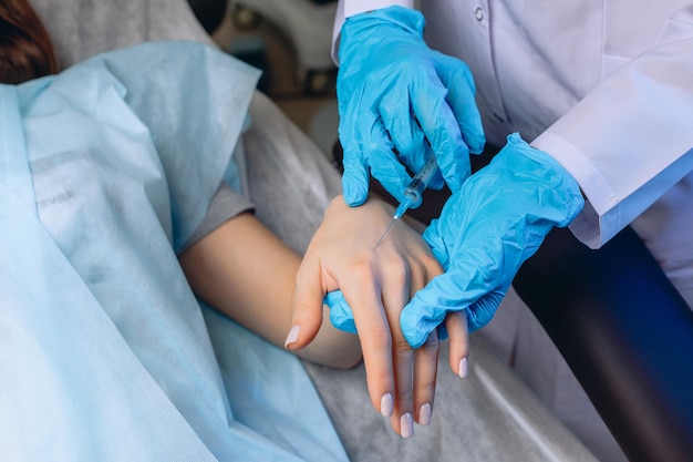 Primer plano de la mano femenina joven bien arreglada. La cosmetóloga da inyecciones en el brazo para el rejuvenecimiento.