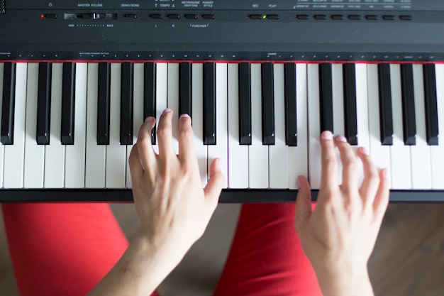 Primer plano de una mano femenina de música clásica tocando el piano o sintetizador electrónico (teclado de piano)