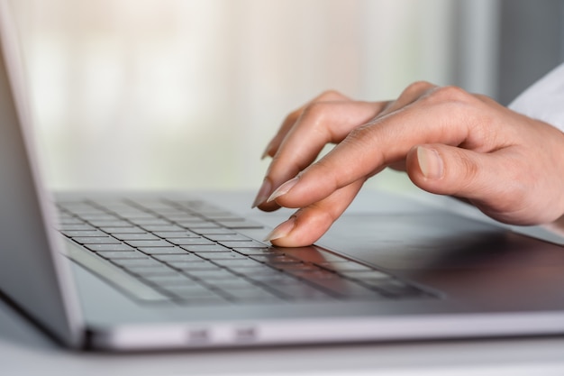 Primer plano mano femenina presionando el botón de la barra espaciadora en un teclado de computadora portátil