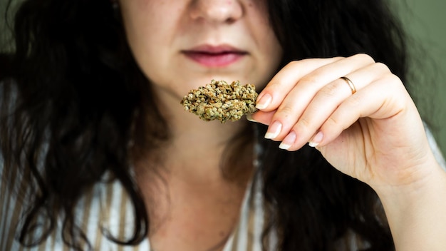 Primer plano de una mano femenina sosteniendo un cogollo de marihuana medicinal Concepto de medicina herbaria y alternativa