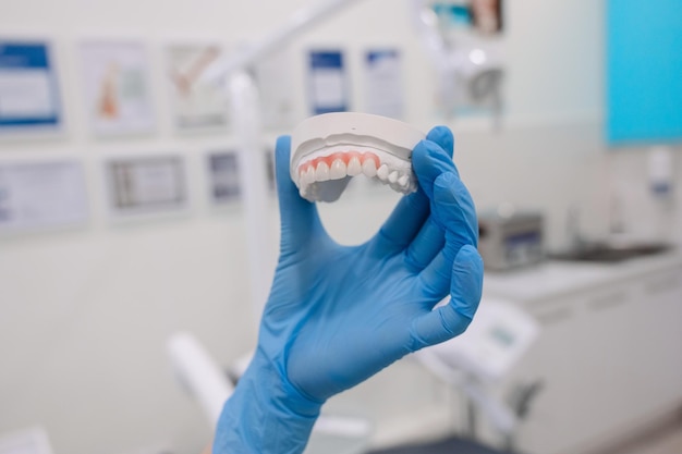 Primer plano de una mano femenina sosteniendo un molde dental