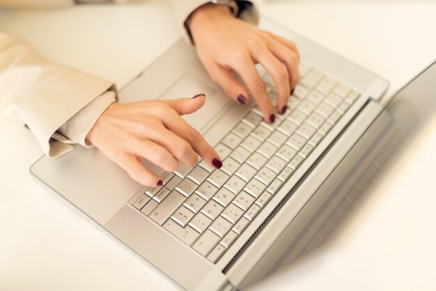 Primer plano de la mano femenina en el teclado de la computadora portátil.