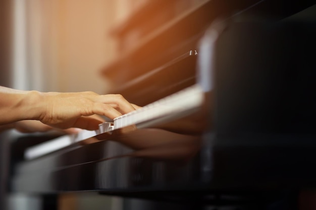 El primer plano de la mano gente hombre músico tocando el teclado del piano con teclas de enfoque selectivo se puede utilizar como fondo