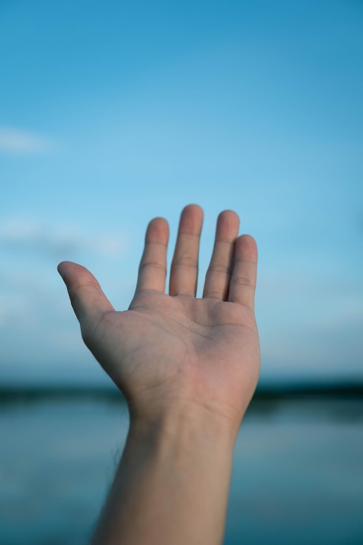 Foto primer plano de la mano gestando contra el cielo azul