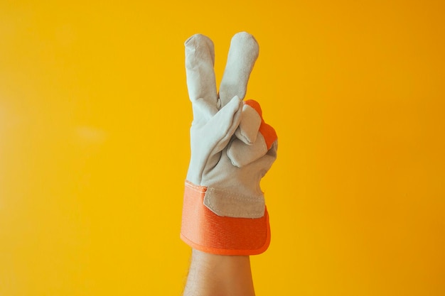 Foto primer plano de una mano con guantes gestando contra un fondo amarillo