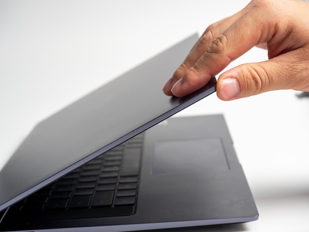 Primer plano de la mano de un hombre abriendo la tapa de una computadora portátil gris Dispositivos modernos para el trabajo y el ocio