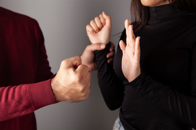 Primer plano de una mano de hombre agresiva agarró la mano de una mujer