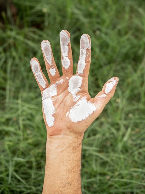 Foto primer plano de la mano de un hombre cubierta de pintura blanca sobre el fondo de hierba verde preservación del concepto de medio ambiente