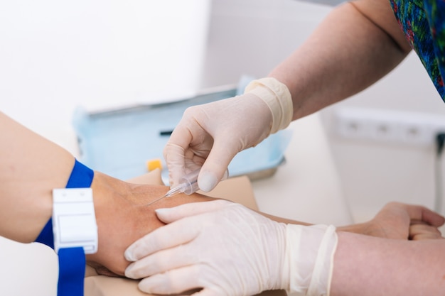 Primer plano de la mano del hombre dando sangre para análisis de sangre bioquímicos