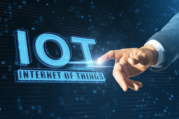 Primer plano de la mano de un hombre de negocios que señala un holograma IOT resplandeciente abstracto en fondo azul concepto de Internet de las cosas