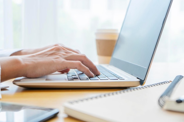 Primer plano de la mano de un hombre de negocios usando una computadora portátil para trabajar y documentos colocados en su escritorio La pantalla está en blanco para insertar medios