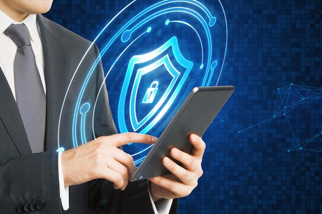 Primer plano de la mano de un hombre de negocios usando una tableta con un holograma de escudo de candado brillante en un fondo azul borroso Concepto de protección web de seguridad y antivirus