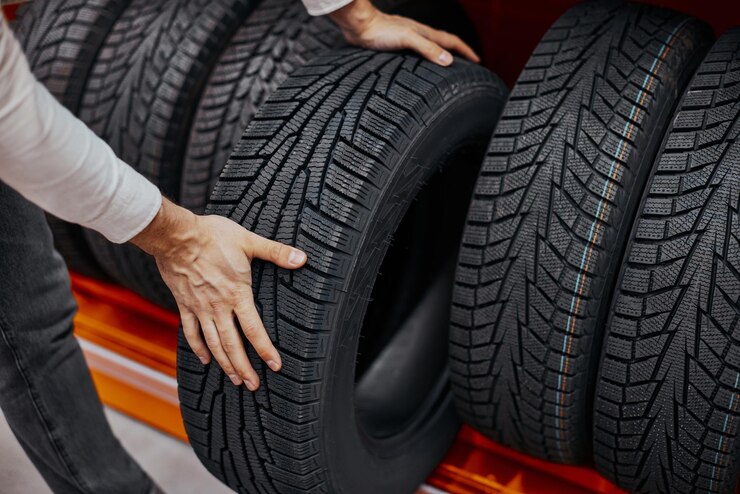Primer plano de la mano de un hombre con neumáticos de coche
