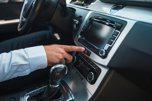 Primer plano de la mano de un hombre con sistema estéreo de audio para el automóvil