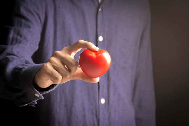 Foto primer plano de la mano de un hombre sosteniendo un símbolo de corazón rojo concepto de fotografía de stock