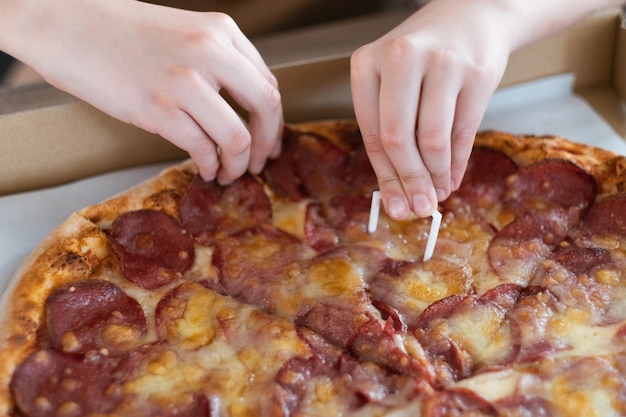 Primer plano de la mano de un hombre tomando una rebanada de pizza de pepperoni Pizza con salami y queso