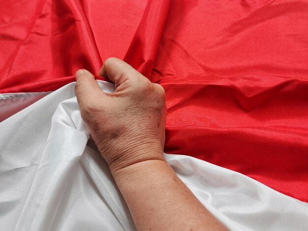 Foto primer plano de una mano humana en una bandera roja y blanca, un símbolo del día de la independencia de indonesia