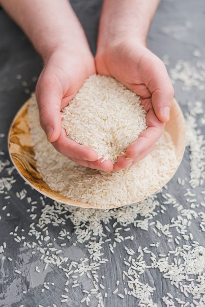 Primer plano de una mano humana con granos de arroz de jazmín blanco crudo