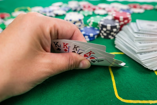 Primer plano de una mano humana con naipes en una mesa de casino verde apuesta Concepto de póquer