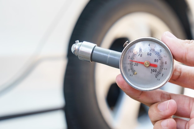 Foto primer plano de la mano humana sosteniendo el medidor contra el coche